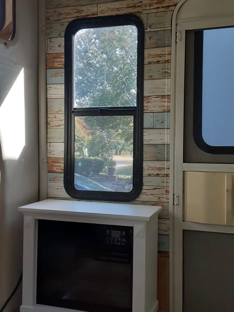 Small electric fireplace with multiple lights and new wallpaper in the background. RV interior updates 